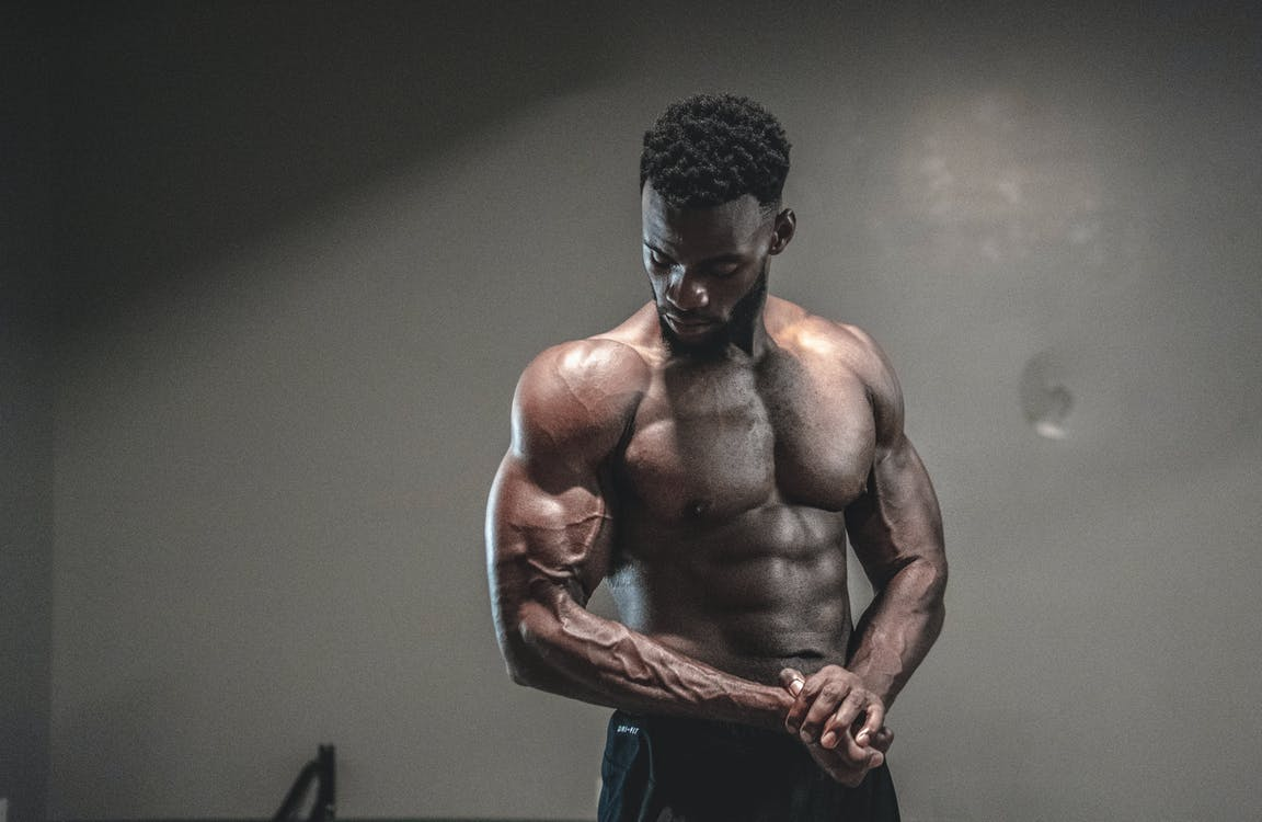 man looking at his muscles after a grueling workout