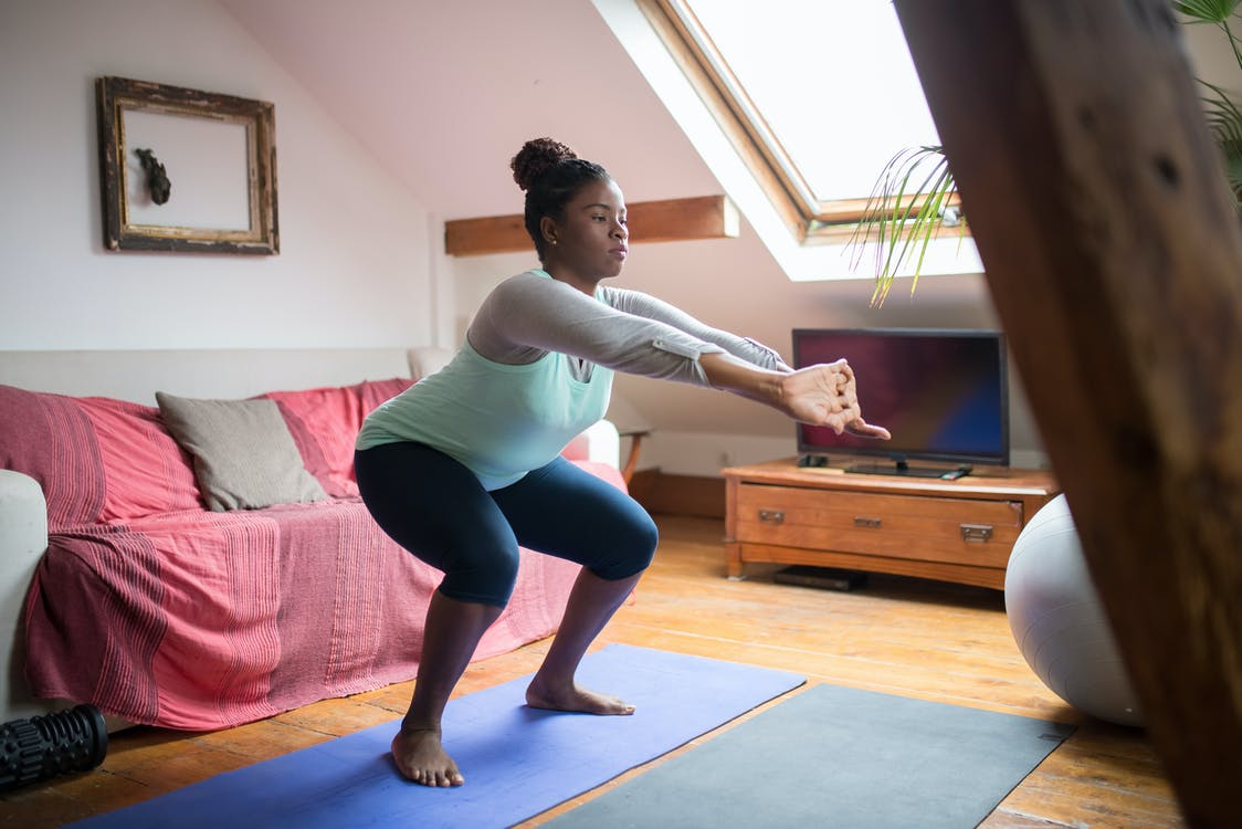 A woman doing a calisthenics squat in her living room
